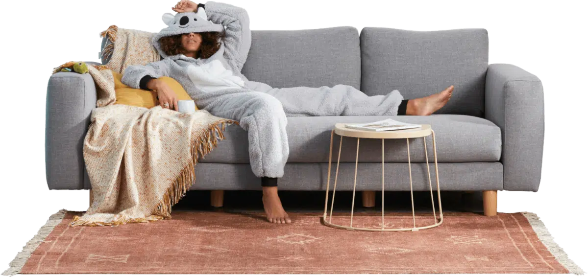 520e681e209b9841fe75e6e6c975496a@2x A woman in a koala onesie slouching on a couch