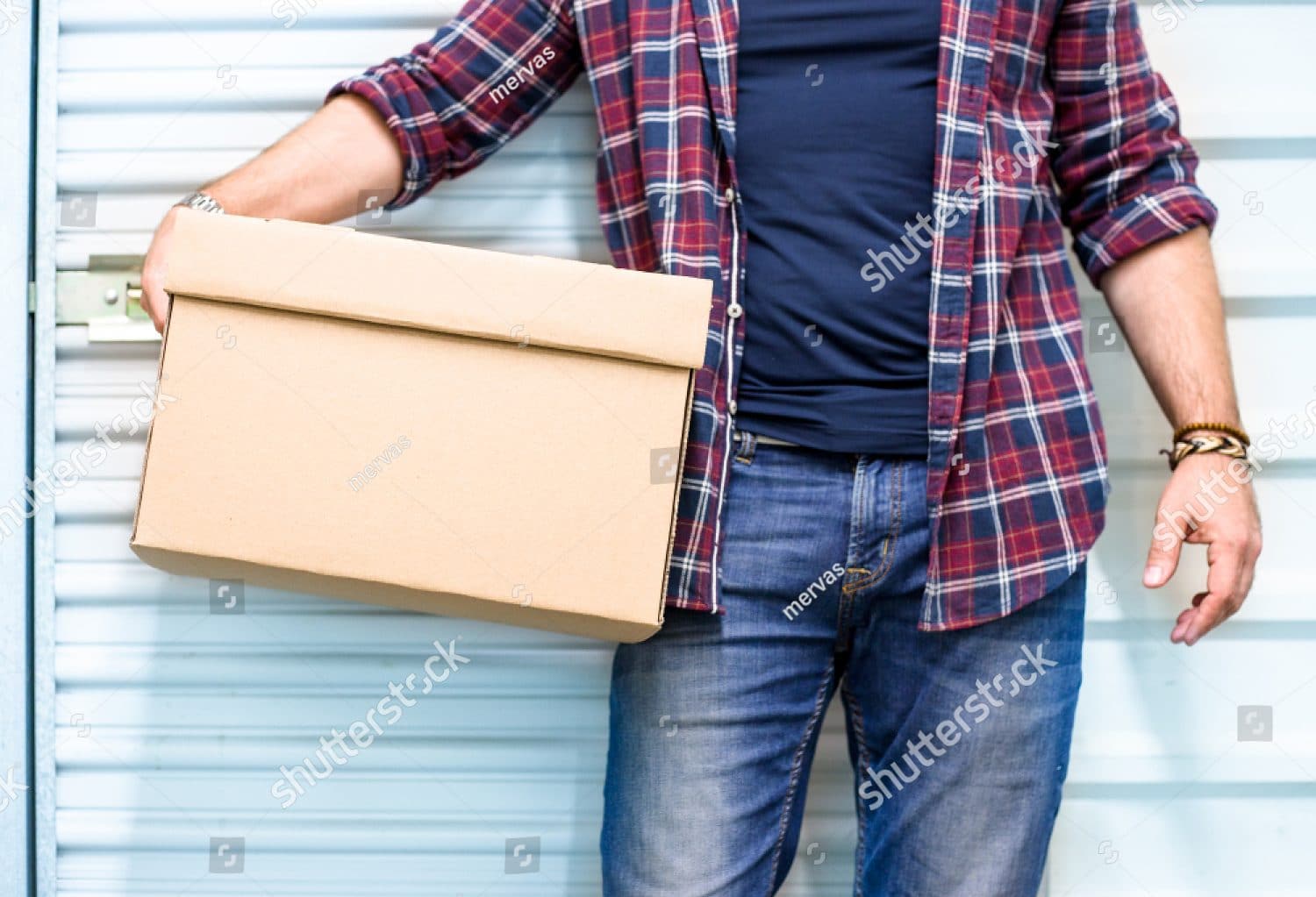 A man in a red flannel carrying a medium sized cardboard box