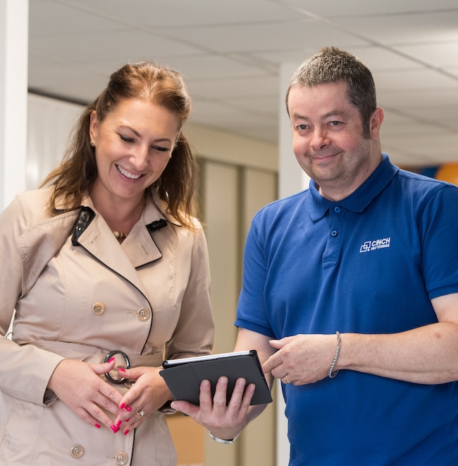 An employee showing his tablet to the woman standing next to him