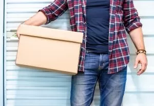 shutterstock_1022658016 A man holding a box outside storage facility
