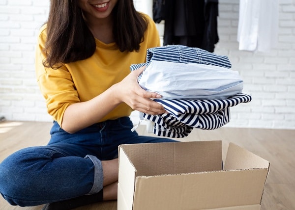 A woman putting folded clothes in a storage box