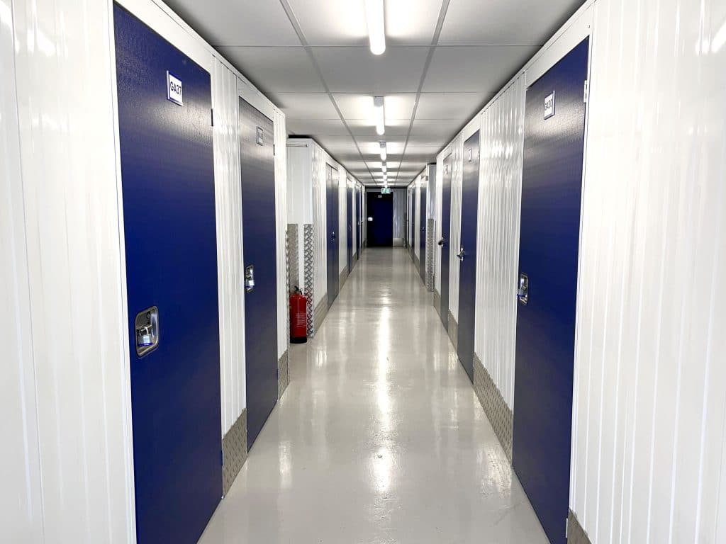 brightly lit corridor of dark blue doors at Cinch Storage facility