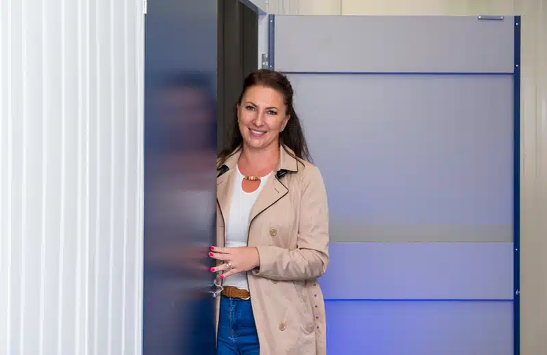 Smiling woman next do blue door of storage unit