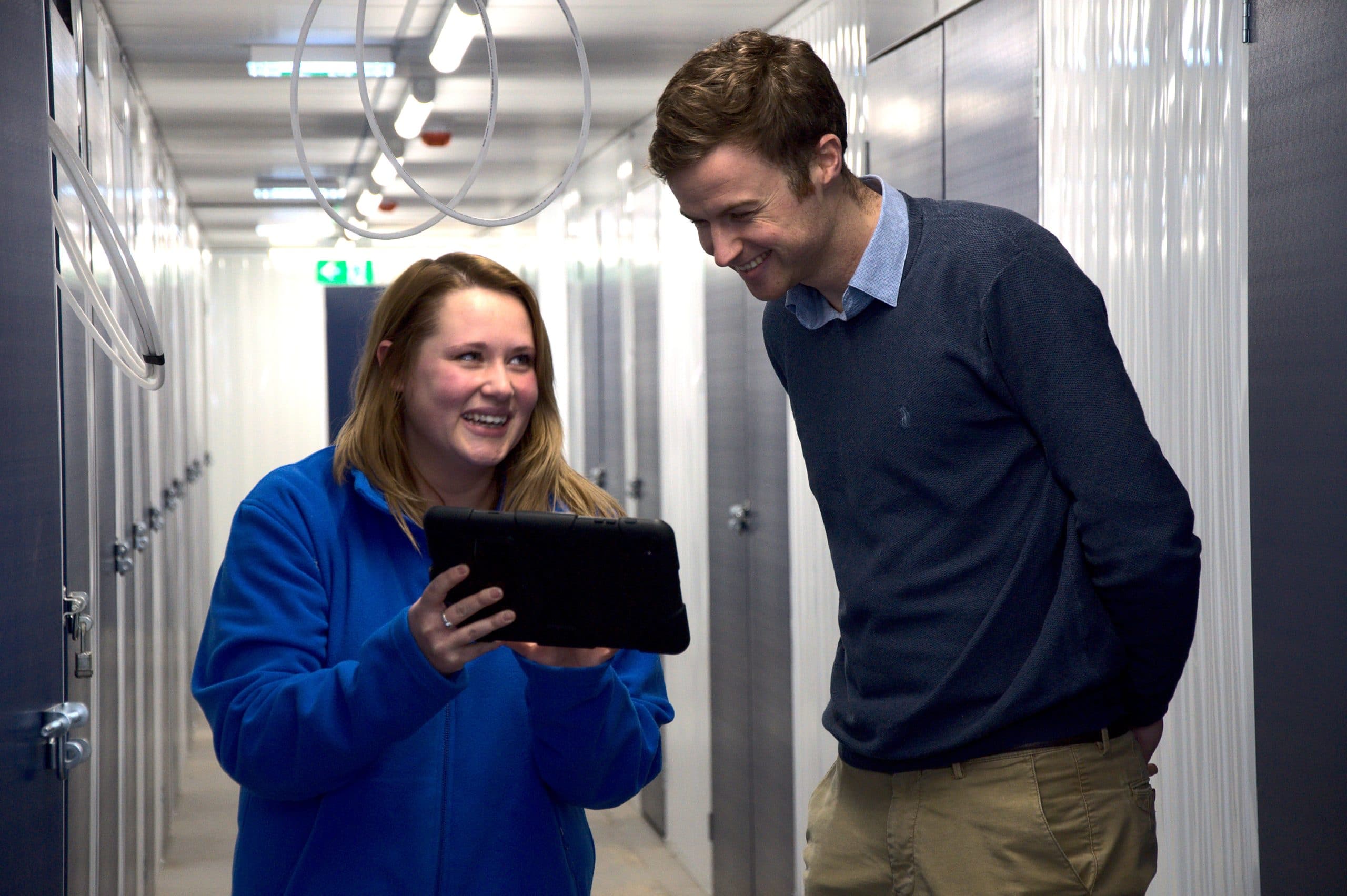 Woman and man smiling over iPad in storage facility