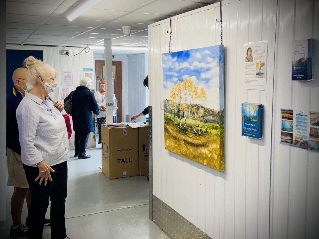 Two spectators viewing a painted canvas at a community art exhibition