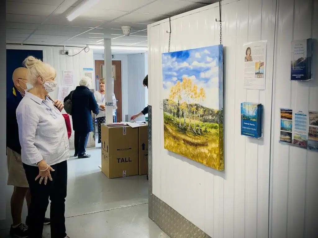 Two spectators viewing a painted canvas at a community art exhibition