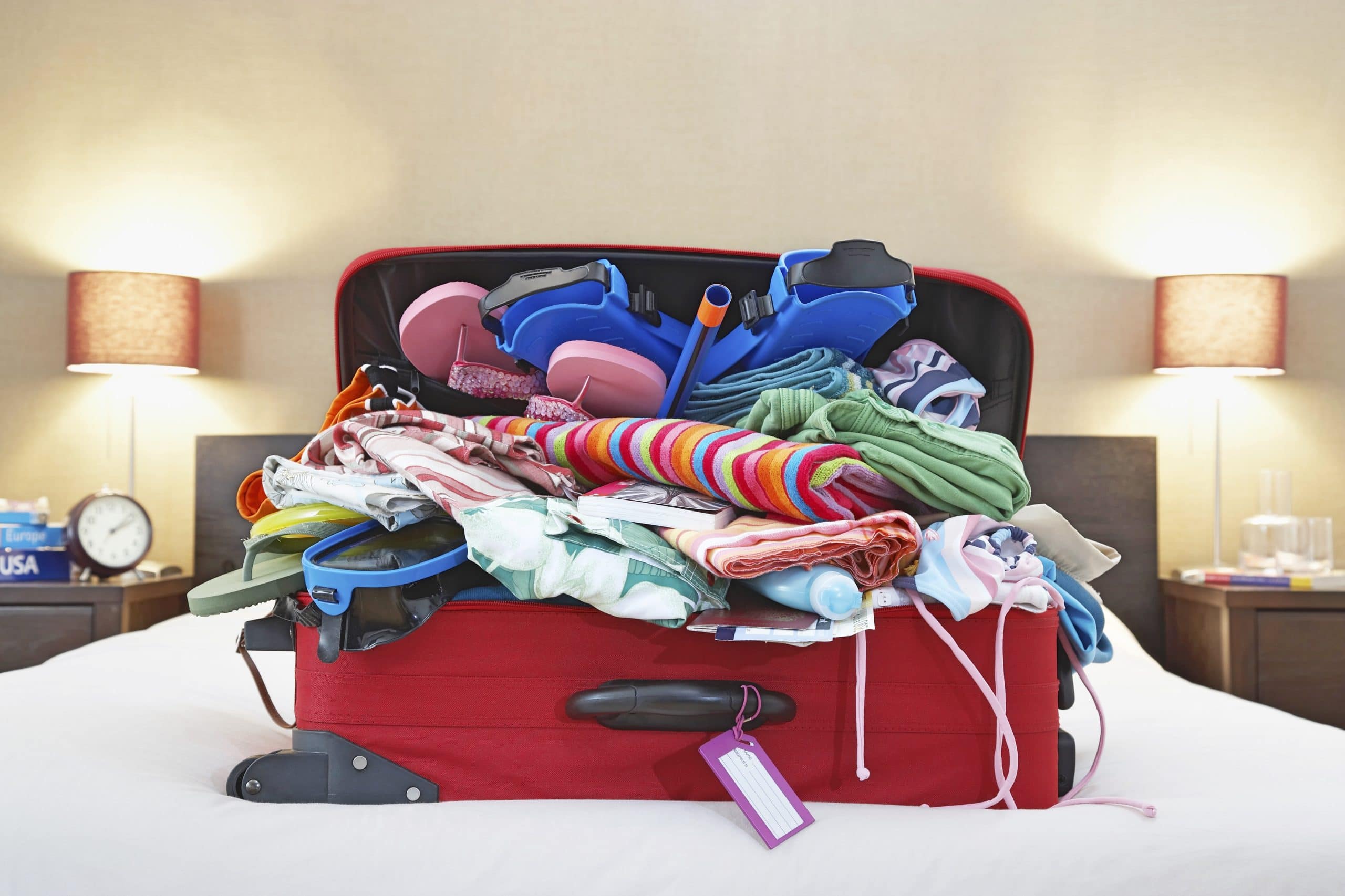 Overflowing suitcase filled with summer holiday clothes