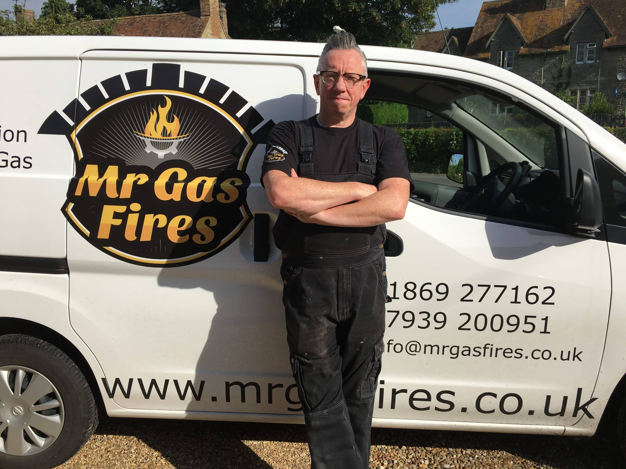 Man with arms crossed leaning against van that reads 'Mr Gas Fires'.