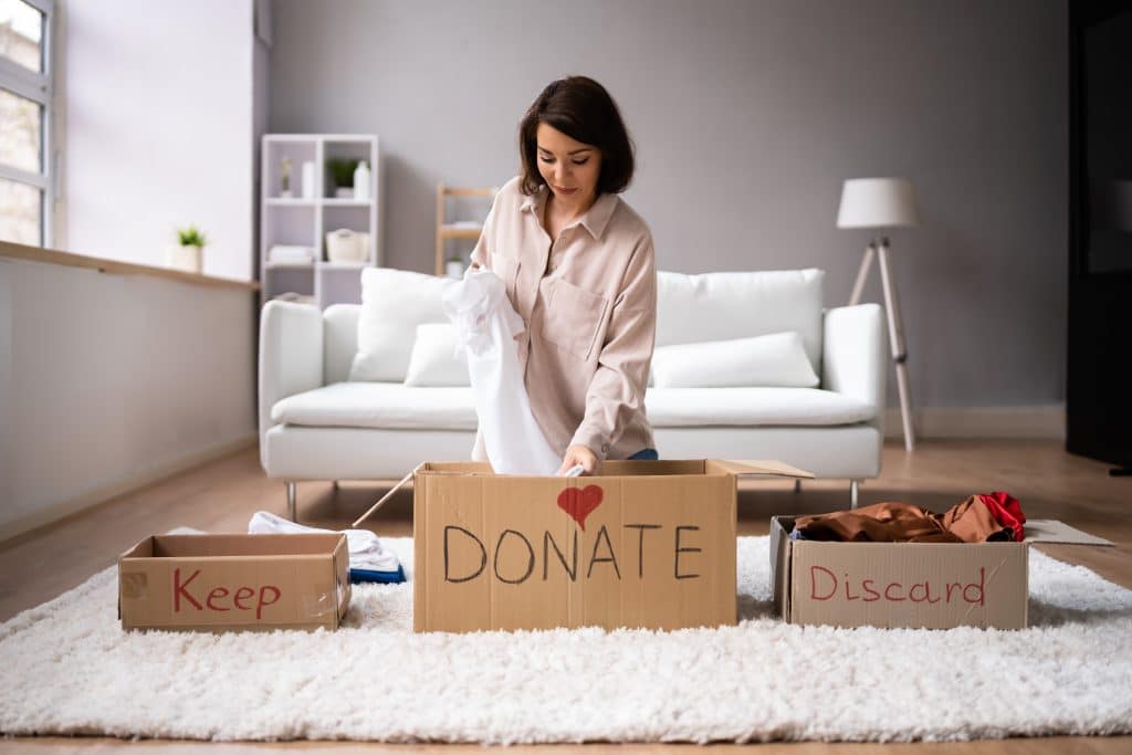 Woman decluttering her home - putting her belongings into keep, donate and discard boxes