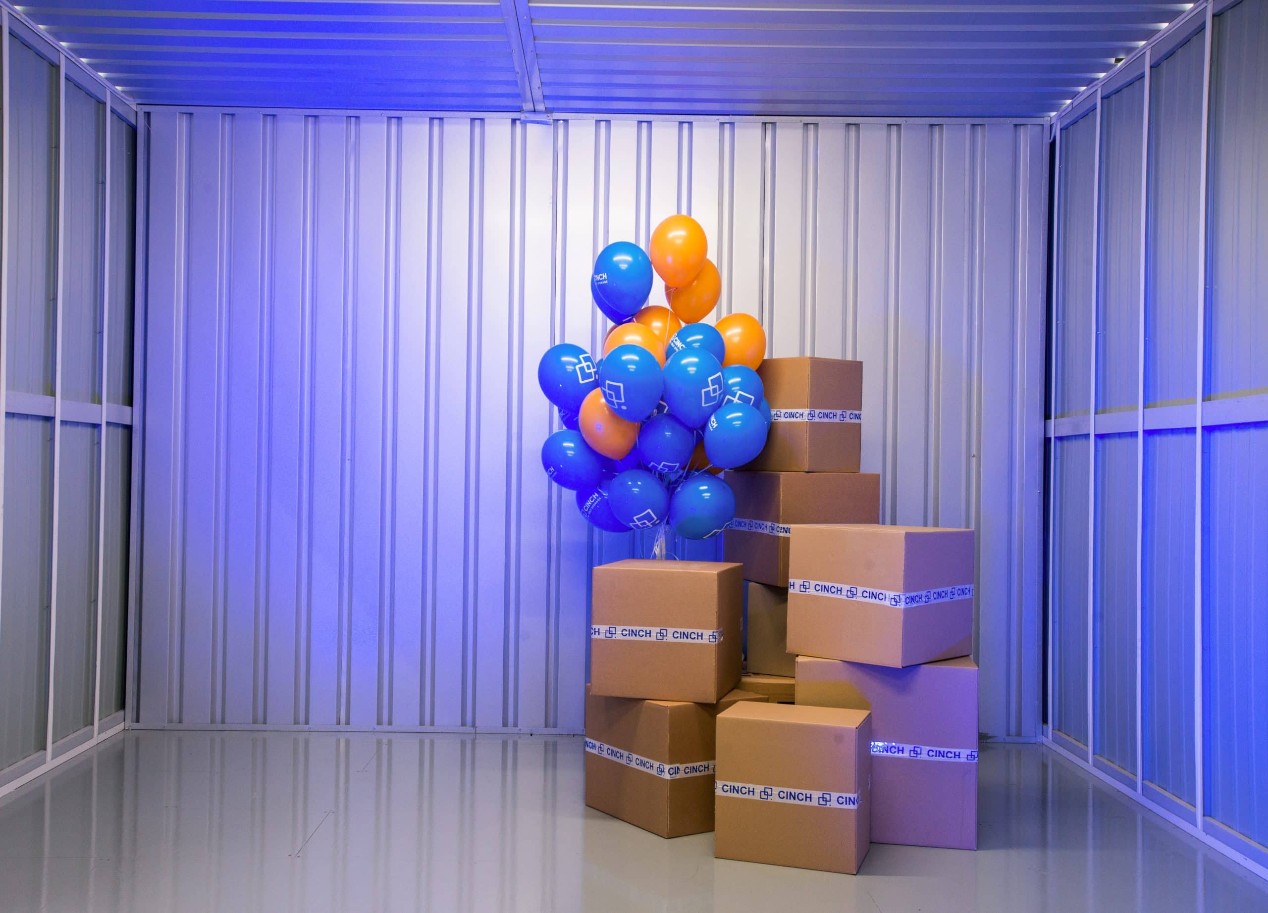 Interior self storage unit in Sittingbourne, blue and orange balloons with cardboard boxes