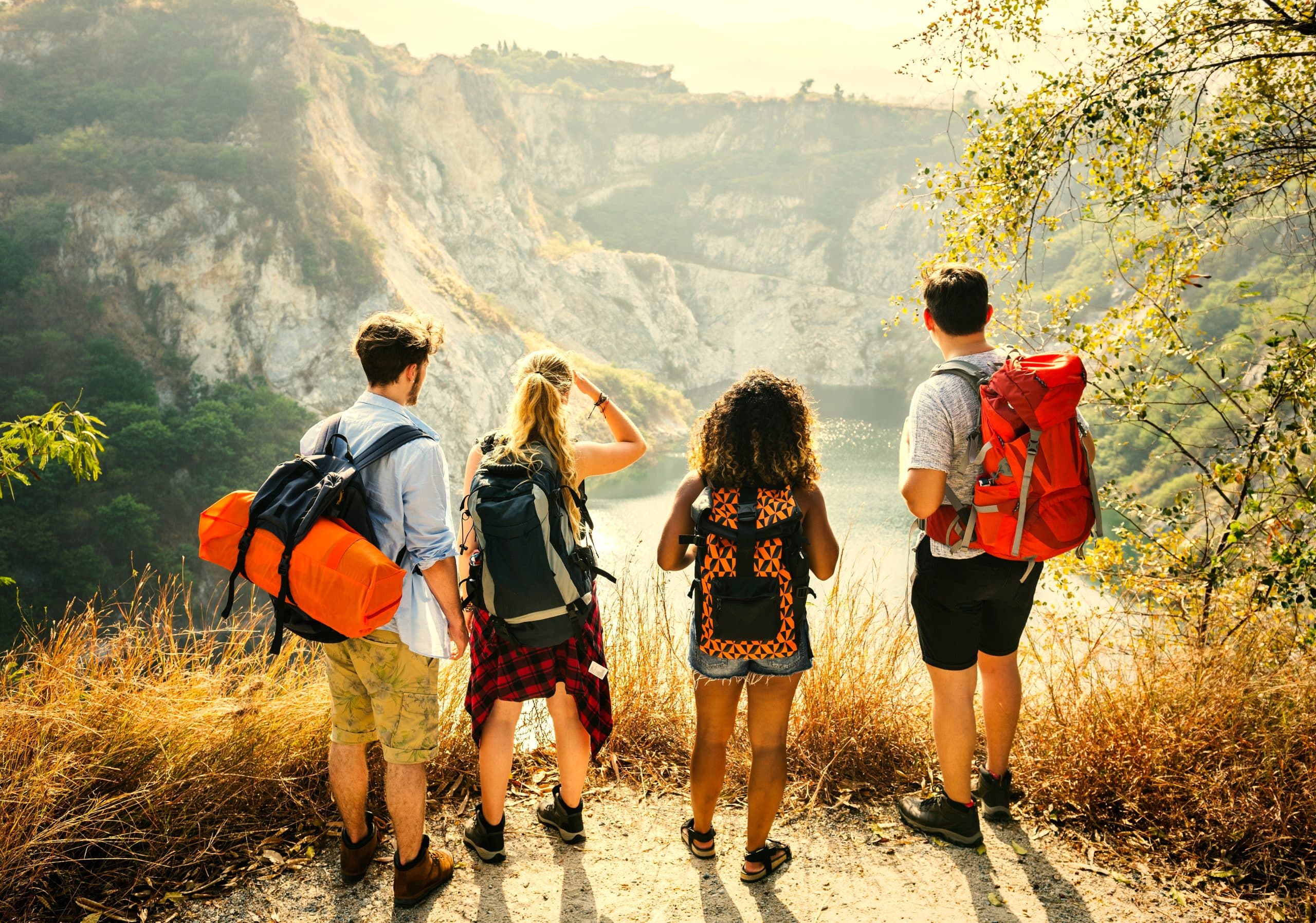 Young people standing looking out over a landscape wearing backpacks