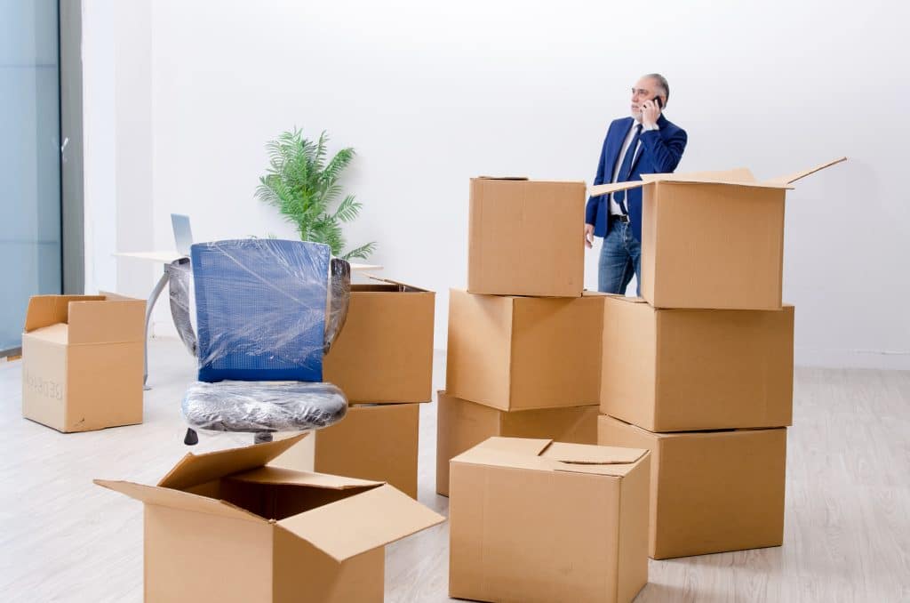 Man standing surrounded by boxes after deciding to downsize his office and move the boxes to a low cost storage unit Mitcham 