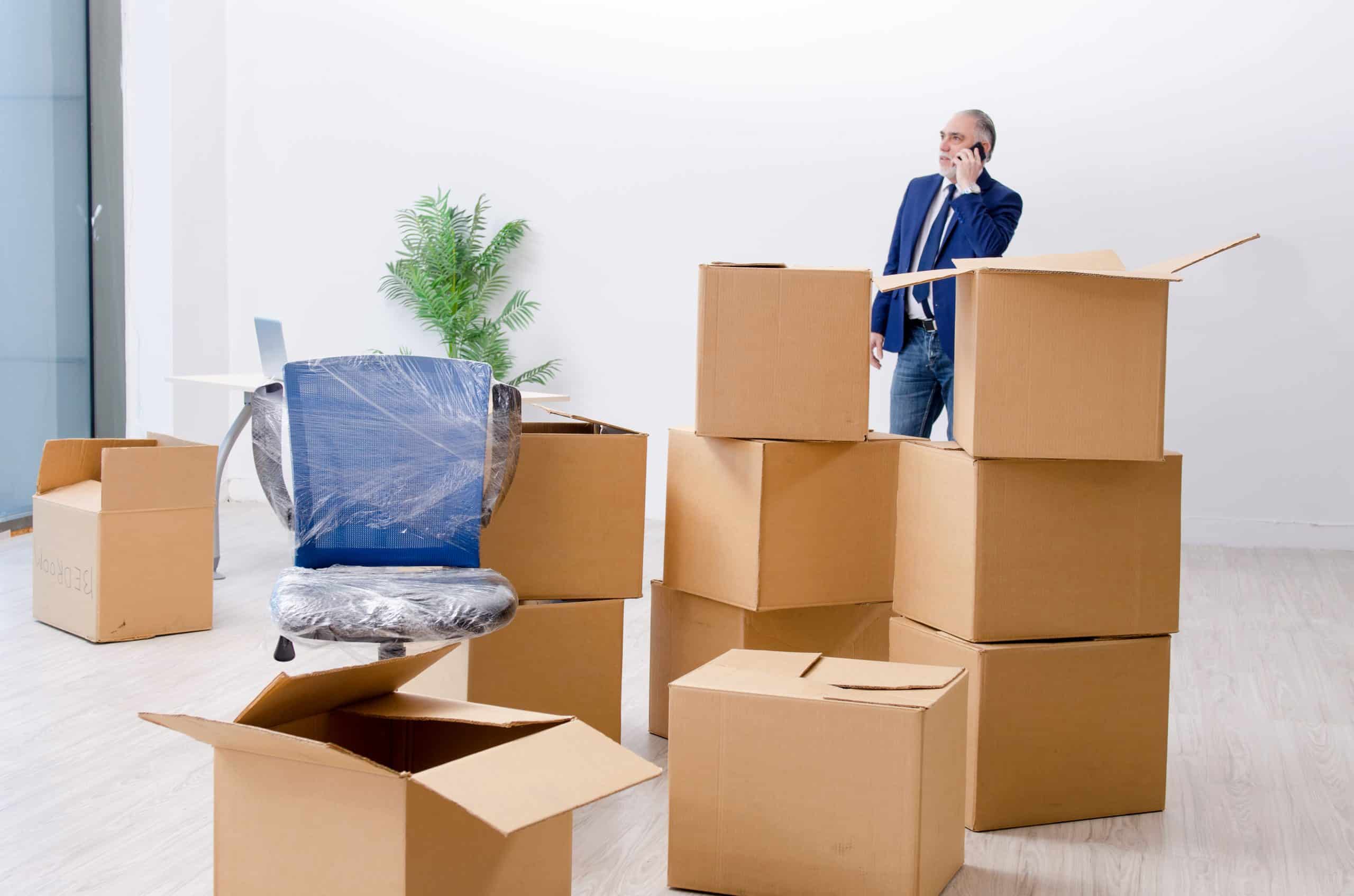 Man standing surrounded by boxes after deciding to downsize his office and move the boxes to a storage unit