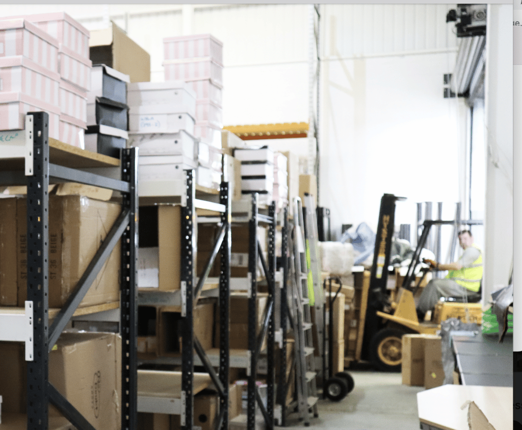Enfield storage - interior of storage space showing racking with shoe boxes stacked on top and a forklift with a driver inside
