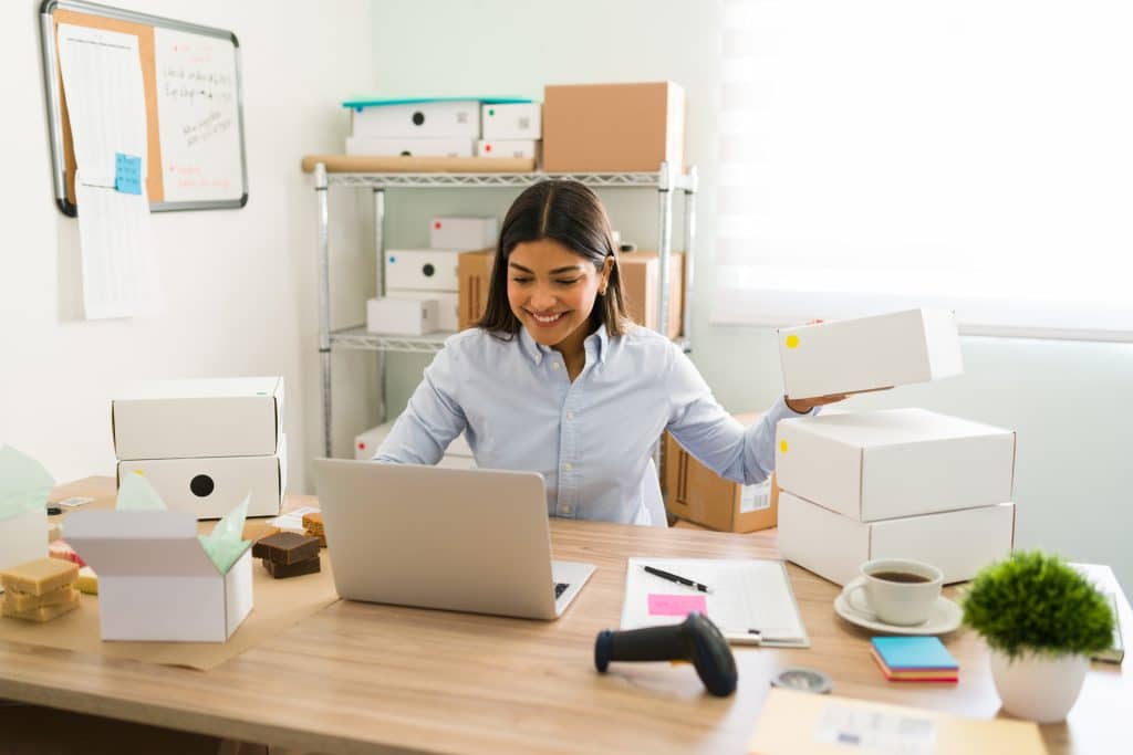 Small office to rent Leighton Buzzard - image shows woman sitting at her desk working through shipping her parcels with a laptop and boxes on the desk