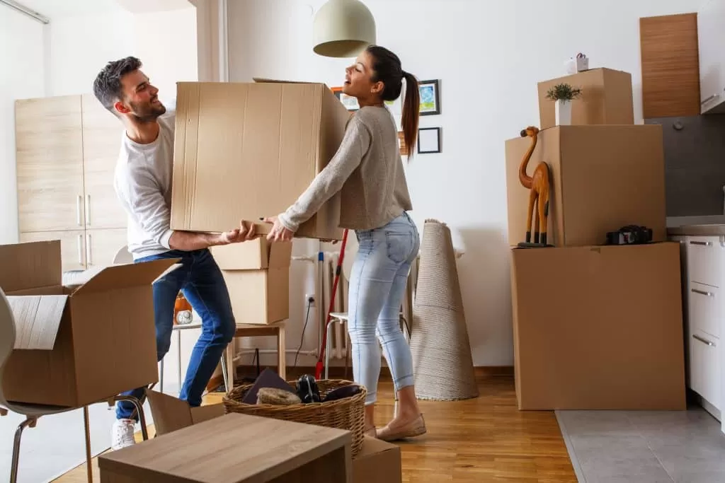 house move storage Enfield - photograph shows a couple holding a packed up moving box between them, with the rest of the room packed up in boxes