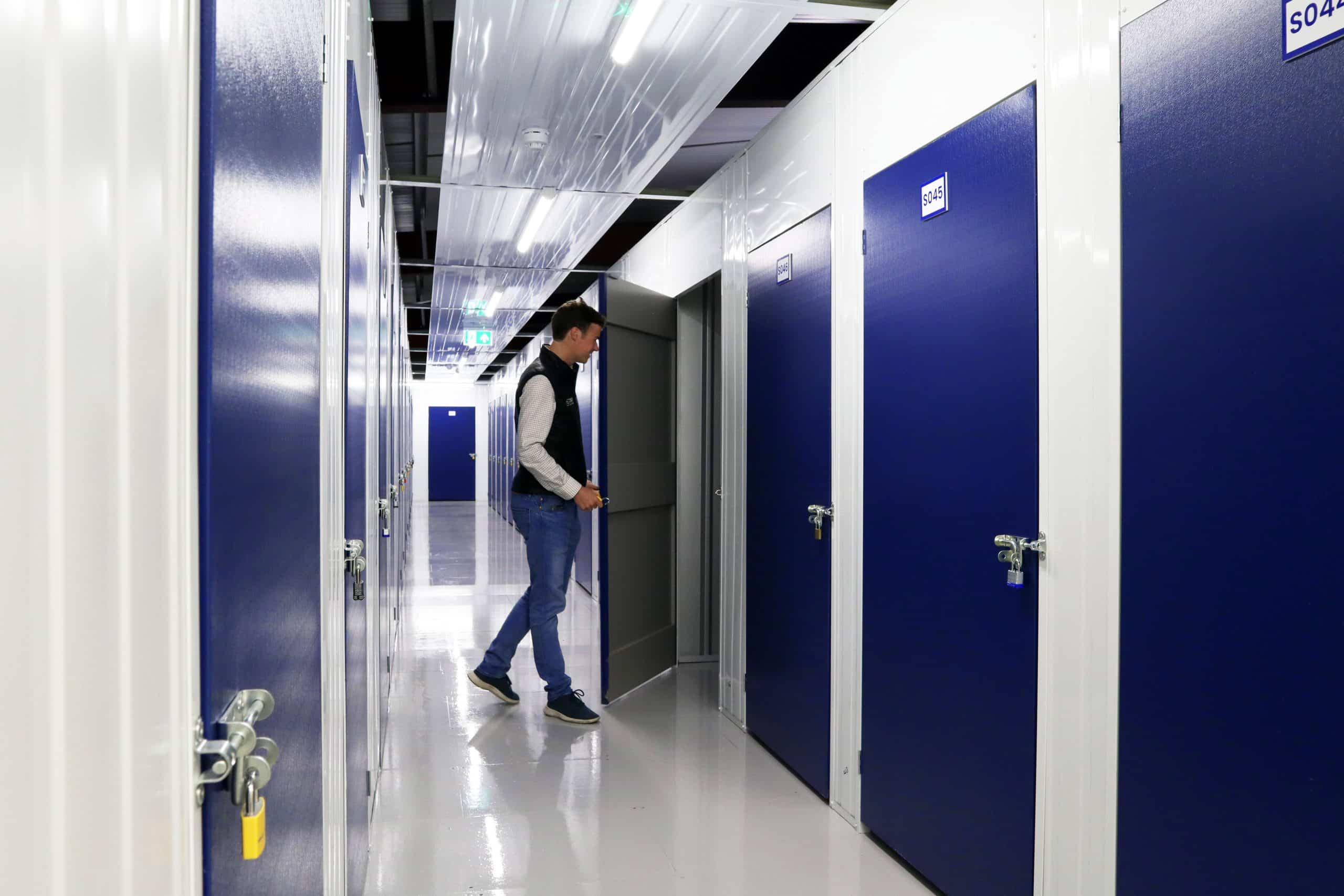 Hectic London Life: Our self storage near Edmonton will bring some peace. Image shows a man opening up a storage unit and a corridor with storage units on both sides.