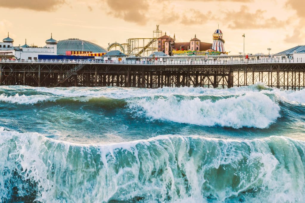 Surf’s Up: How our storage in Brighton will give you the room to surf. Image shows Brighton pier with big waves in front and a cloudy moody sky