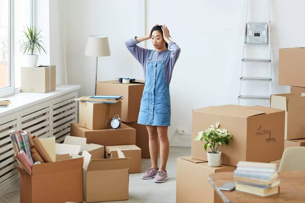 House move storage - image shows a woman with her hands on her head surrounded by cardboard boxes and half-packed boxes