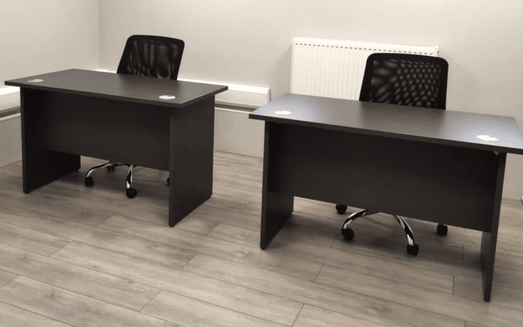 Office to rent in Brighton. Image shows two desks on a wooden floor with chairs behind the desk sitting in front of a radiator. 