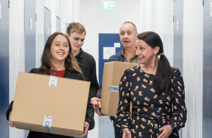 storage_for_students. Image shows daughter, mother and father carrying boxes towards their storage unit.
