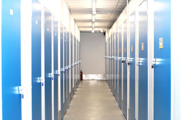 Self storage environmental benefits. Image shows a corridor with blue doors on either side leading to storage units.