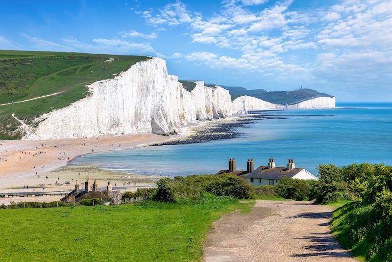 Top things to do in Seaford. Image shows the Seven Sisters Chalk cliffs and the coastguard cottages during a eraly summer day, Seaford, East Sussex, England