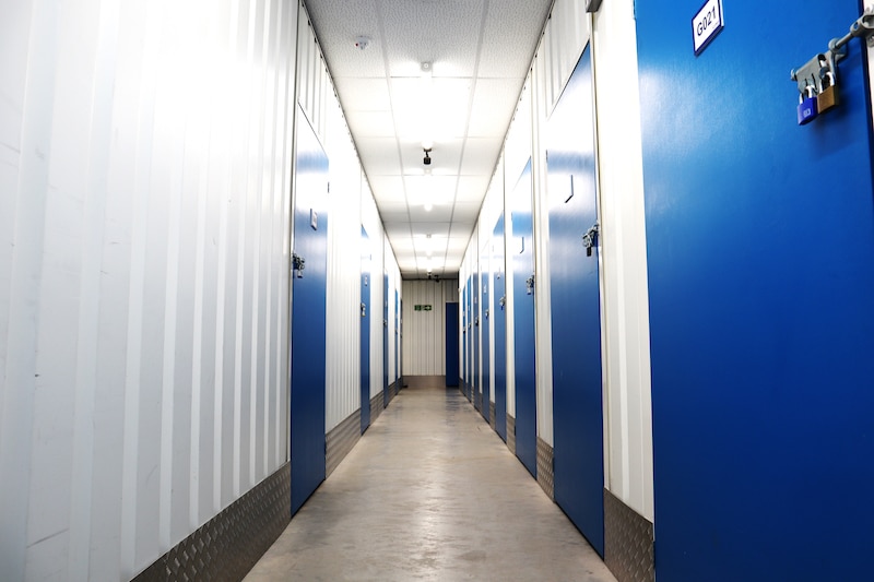 What can't you store in self storage? Image shows corridor of storage units with blue doors