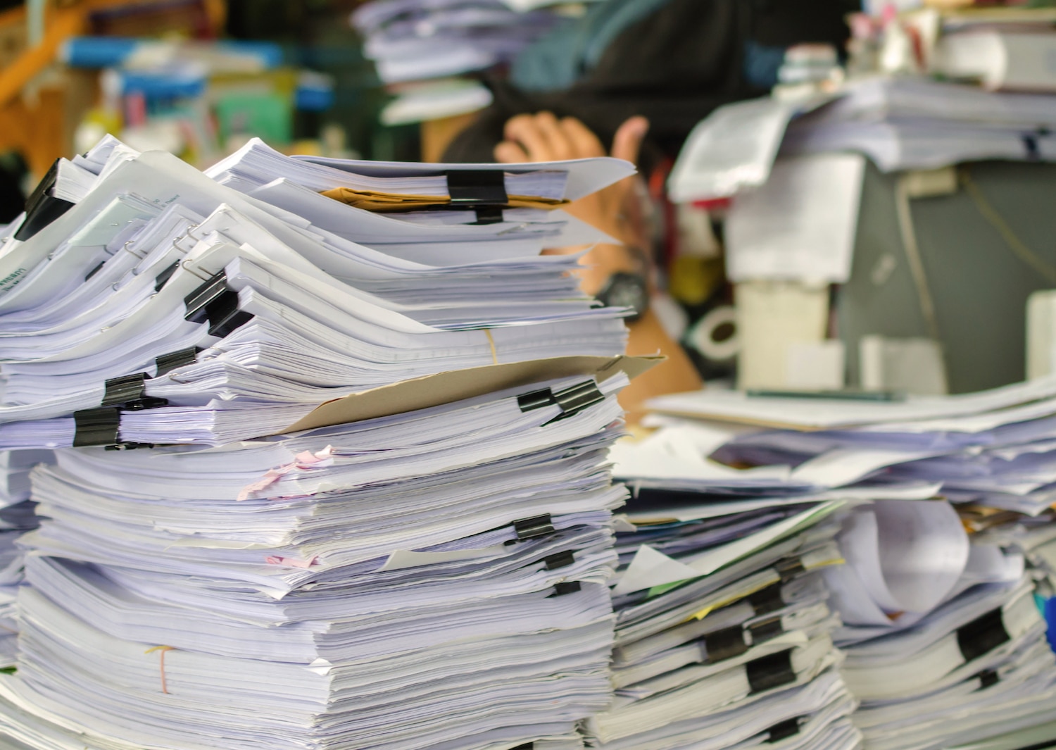 5 Benefits of Huntingdon business storage. Pile of documents on desk stack up high waiting to be managed.