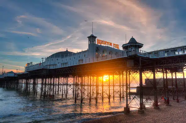5 Best places to live in Brighton and Hove : A comprehensive guide. Image shows Brighton Pier, England at sunset.