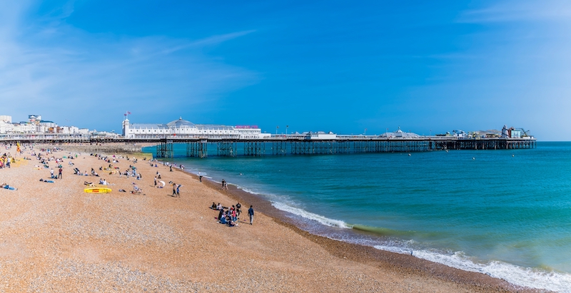 Is Brighton a nice place to live? Image shows a view along the beach towards the pier in Brighton, UK in summertime