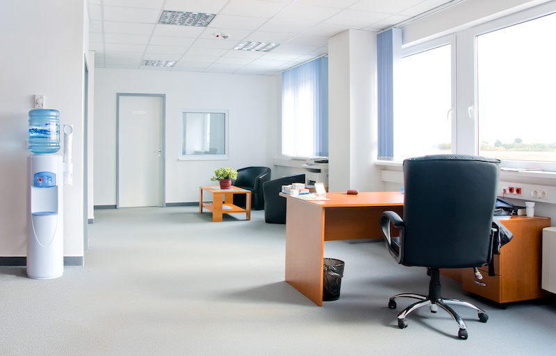 Serviced offices vs managed offices. Image shows a small and simple office interior with white walls and wooden desks
