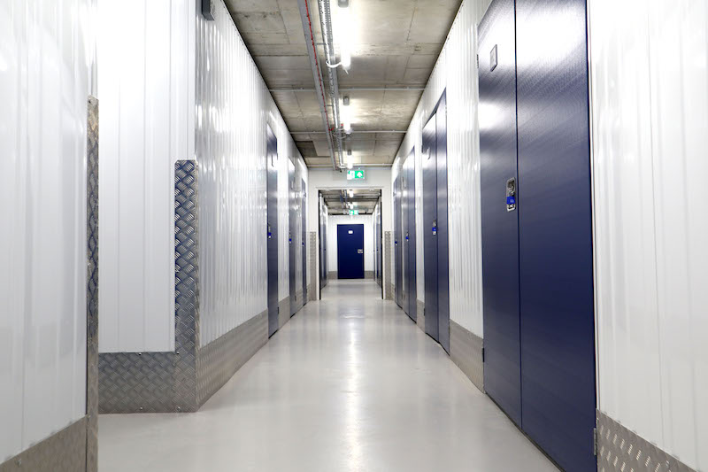 What is climate controlled storage. Image shows the interior of a corridor with blue storage unit doors.