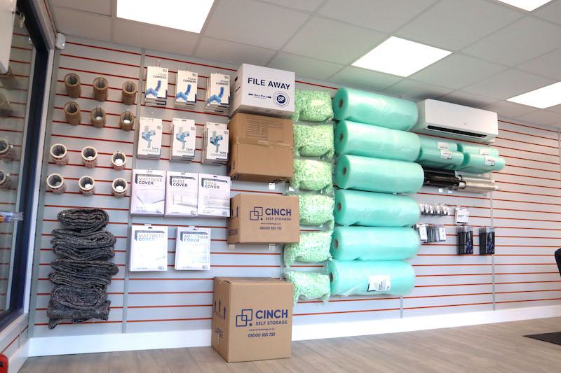 What is the best day to move house? Image shows a reception area of Cinch Self Storage with bubble wrap, cardboard boxes and moving materials displayed on the wall.