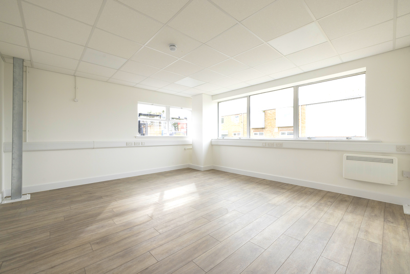 Office to rent in Seaford. Image shows an empty office space with white walls, large windows and wooden floor.