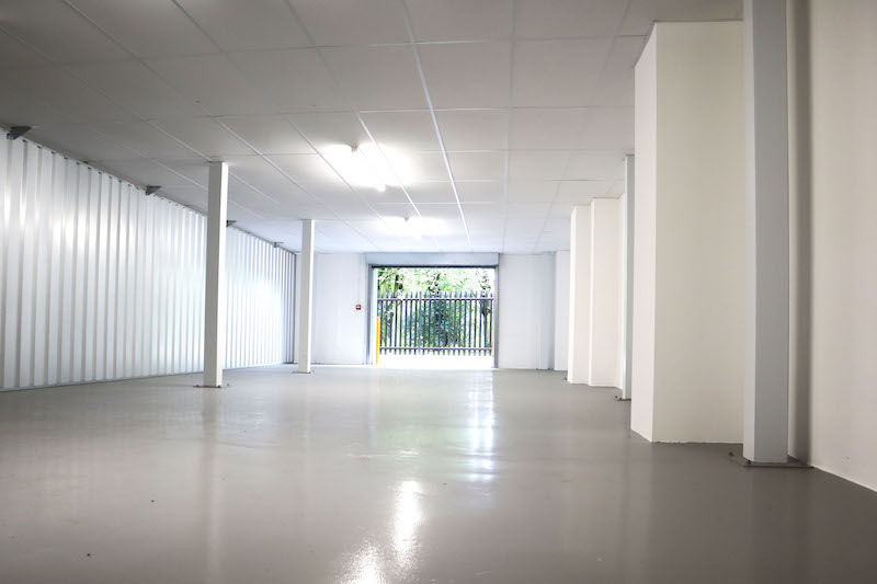 Business storage in Earlsfield. Image shows the inside of an Enterprise unit with open roller doors and a vast open space with white walls and grey resin floor.