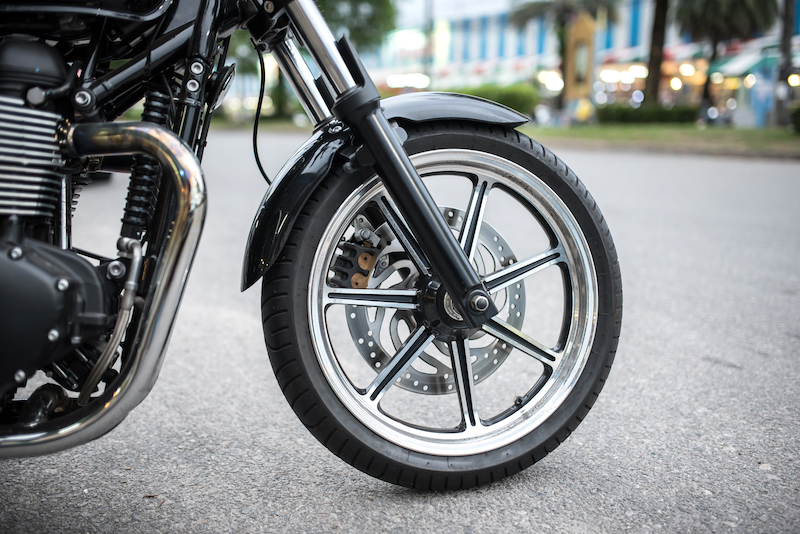 Motorcycle storage tips. Image shows the front wheel of a motorcyle parked in the street.