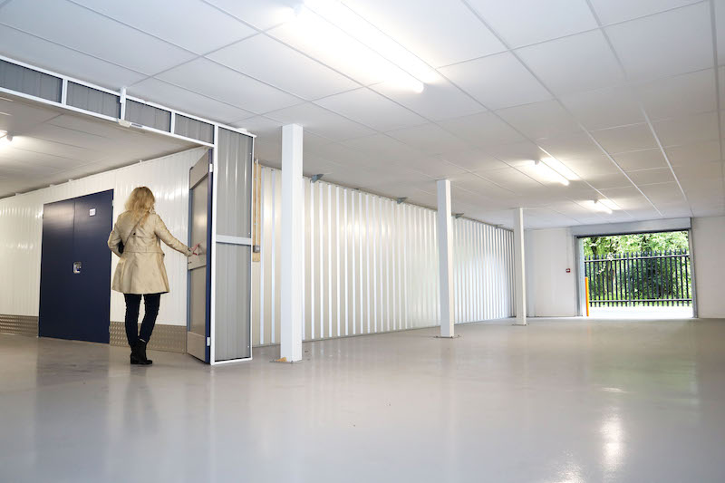 Business storage in Wimbledon. Image shows a woman standing in the doorway of an empty Enterprise unit in Cinch Self Storage.