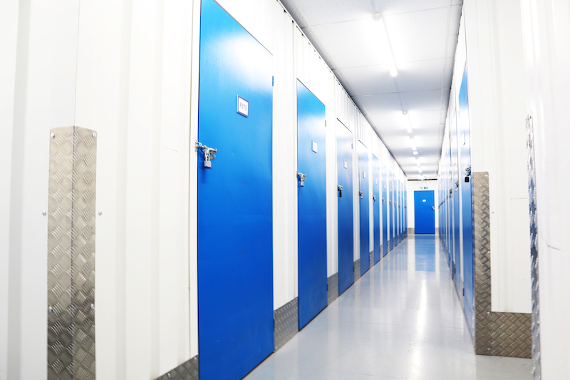 House move storage Southend. Image shows a bright and light corridor with blue storage unit doors.