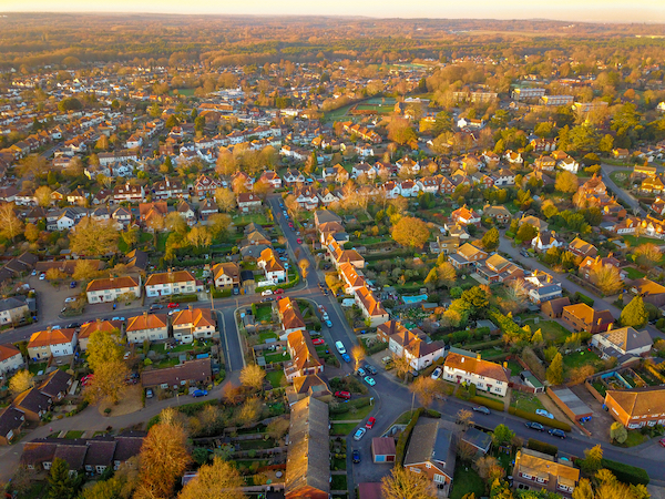 Is Woking a nice place to live? Image shows  an aerial view of suburban housing with trees at sunset