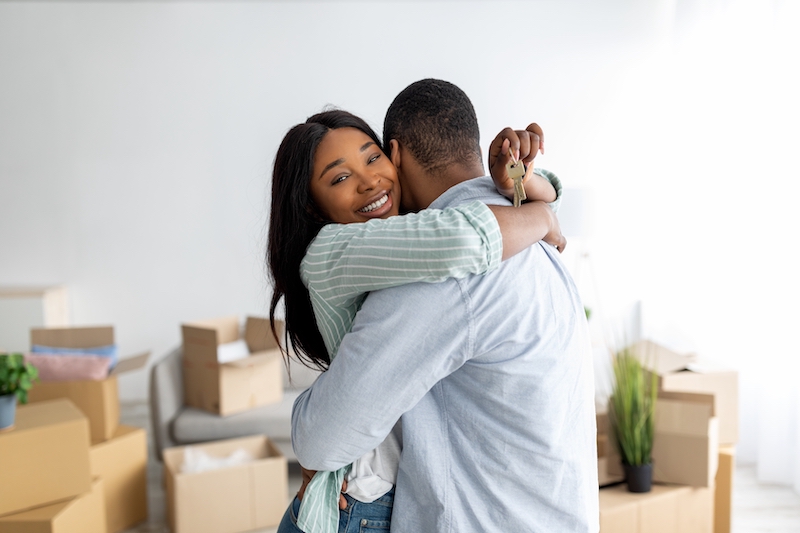 Storage Houghton Regis. Image shows a woman holding a house key and embracing her husband, standing in their new home