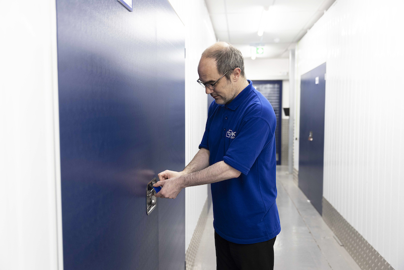 Storage unit Seaford. Image shows a Cinch Self Storage employee opening up a storage unit.