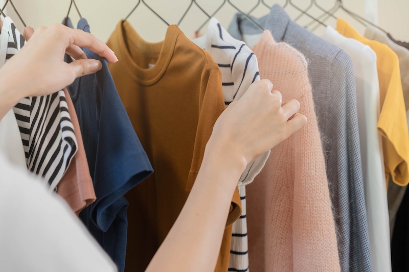 Storage units Dunstable. Image shows a clothes rail with a hand touching a striped white t-shirt.