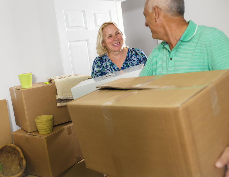 Godmanchester Storage. Image shows a retired couple decluttering their home, standing with cardboard boxes. 