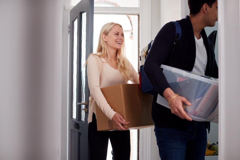 Self storage Dunstable. College Student Couple Carrying Boxes Moving Into Accommodation Together