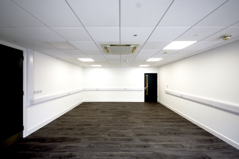 Chippenham office to let. Image shows an empty office with brown wooden flooring and white walls. 