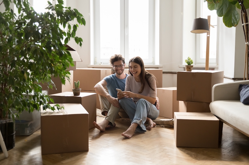 Low cost storage Newbury. Image shows a couple sitting on the floor in their new home with boxes and plants around them.