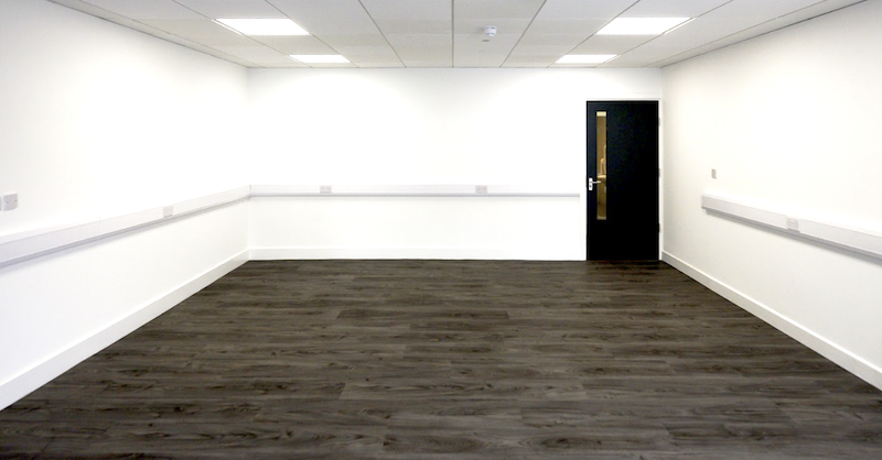 Office Newmarket. Image shows empty office with white walls and dark wooden floor. 