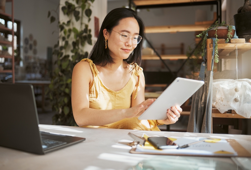 Office Woking. Image shows woman holding a tablet at her desk in her office.