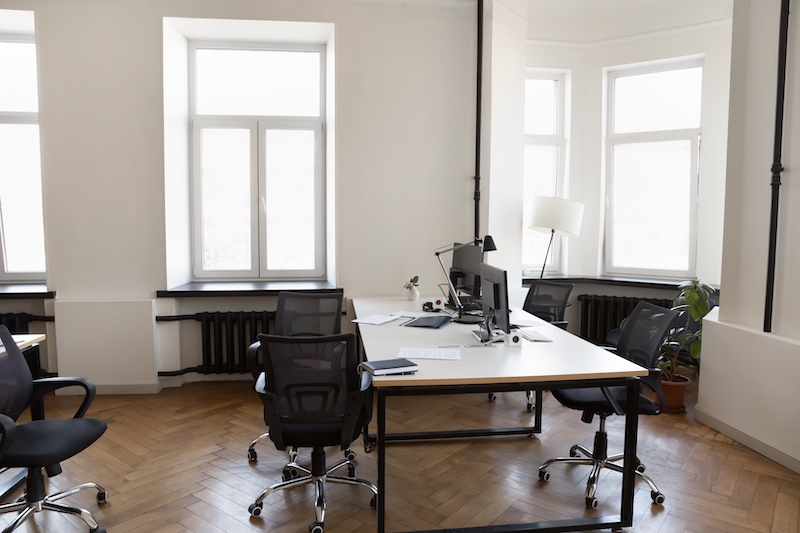 Enfield office to let. Image shows a bright office with wooden flooring, white desks and black office chairs.